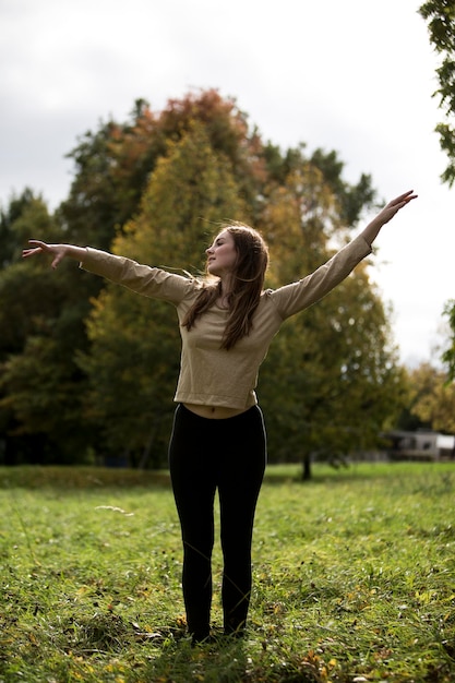 Zdjęcie pełna długość młodej kobiety tańczącej w parku
