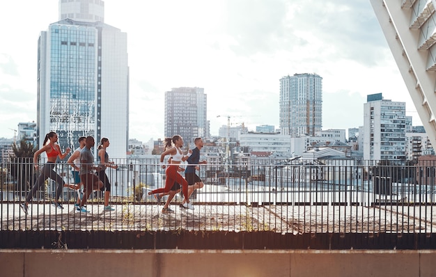 Pełna długość młodych ludzi w sportowej odzieży biegającej podczas ćwiczeń na moście na świeżym powietrzu