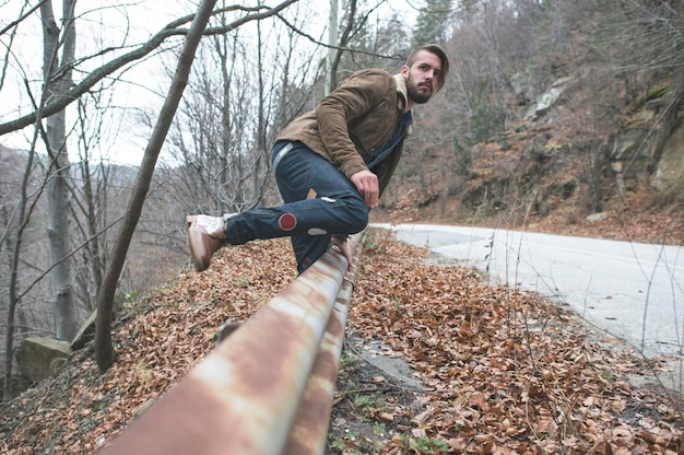 Zdjęcie pełna długość modnego człowieka przez balustradę na drodze