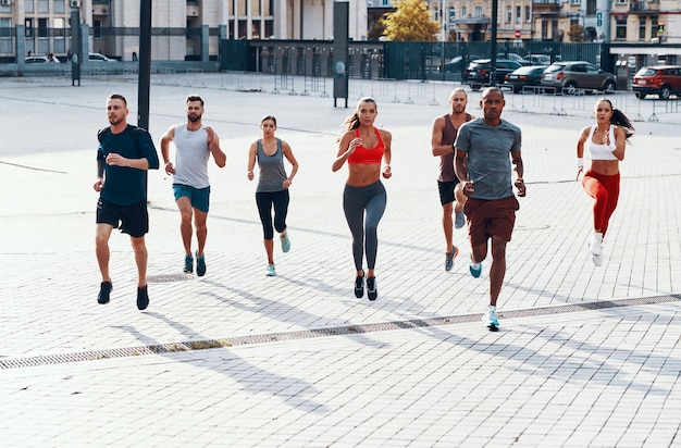 Pełna długość osób w odzieży sportowej biegających podczas ćwiczeń na chodniku na świeżym powietrzu