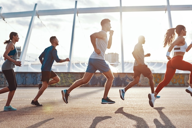 Pełna długość osób w odzieży sportowej biegających podczas ćwiczeń na chodniku na świeżym powietrzu