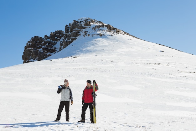 Pełna długość para z narciarskimi deskami na śniegu