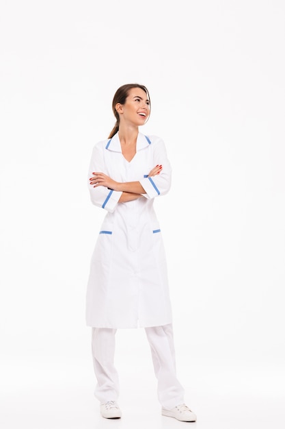 Pełna Długość Pewnie Młoda Kobieta Lekarz Ubrany W Mundur Stojący Na Białym Tle Nad Białą ścianą