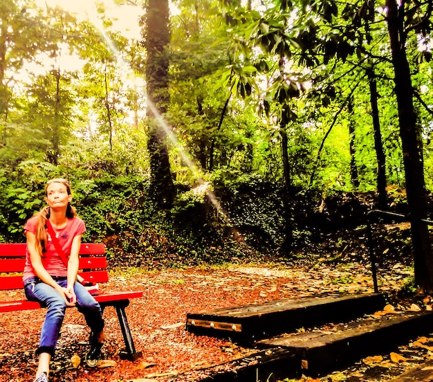 Zdjęcie pełna długość przemyślanej młodej kobiety siedzącej na ławce w parku