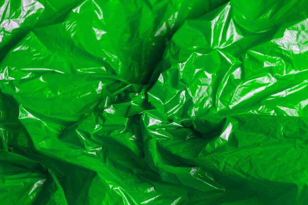 Zdjęcie pełna klatka zbliżenia tło zielonej zmarszczonej cienkiej folii plastikowej