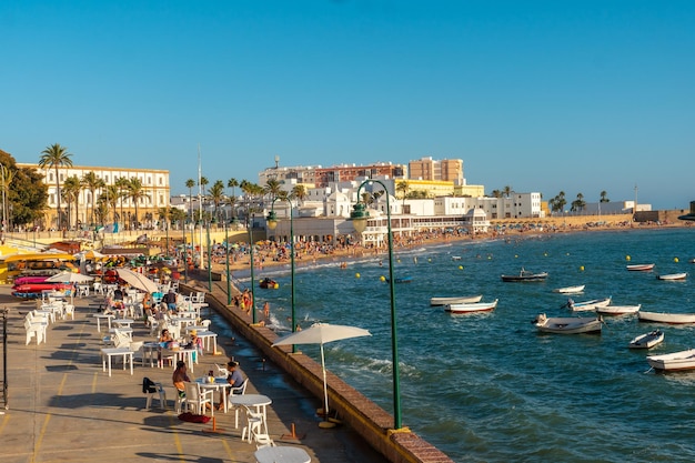 Pełna turystyki plaża La Caleta w letnim zachodzie słońca w mieście Kadyks Andaluzja