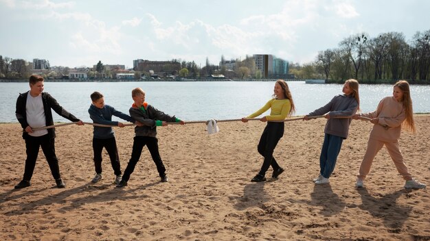 Zdjęcie pełne ujęcie dzieci bawiących się w przeciąganie liny na plaży