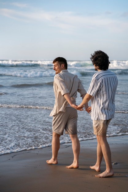Zdjęcie pełne ujęcie gejów trzymających się za ręce na plaży