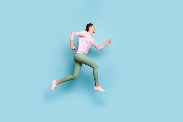Zdjęcie pełne zdjęcie pięknej pani skaczącej wysoko, pędzącej linii mety bieganie mistrz maratonu konkurencyjna dusza nosić swobodny różowy sweter zielone spodnie izolowane niebieski kolor