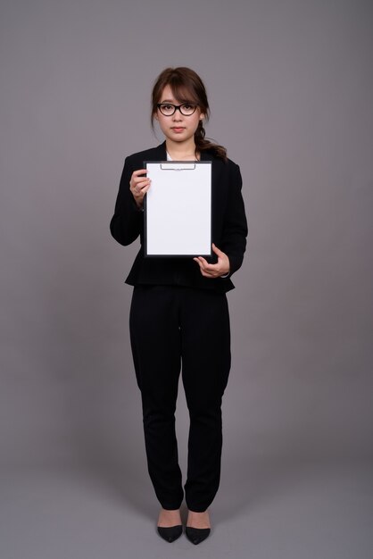 Pełnej długości portret młodej bizneswoman azjatyckiego stojącej
