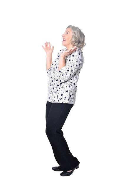 Pełnej długości, szczęśliwa starsza kobieta pozuje na białym tle