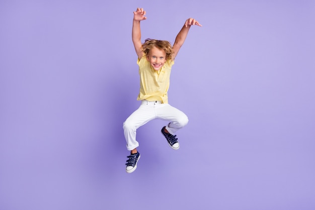Pełnej długości zdjęcie upiornego małego chłopca z wyskoku z pazurami w spodniach z t-shirtu na fioletowym tle