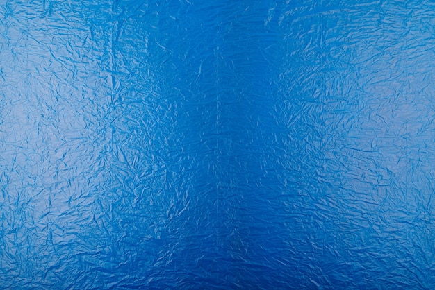 Pełnoklatkowe płaskie tło i tekstura zmiętej niebieskiej folii z tworzywa sztucznego