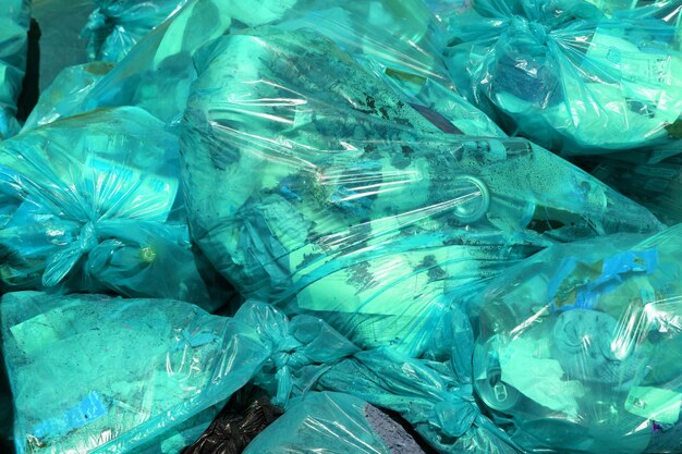 Pełnoklatkowe tło turkusowych plastikowych worków na śmieci z ogólnymi odpadami domowymi