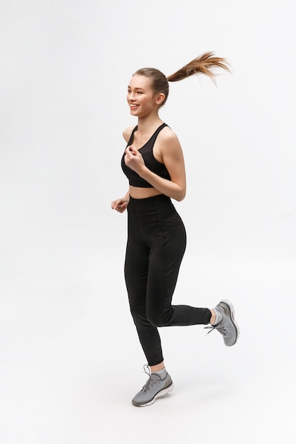 Pełnometrażowe zdjęcie sportowej kobiety biegnącej w studio