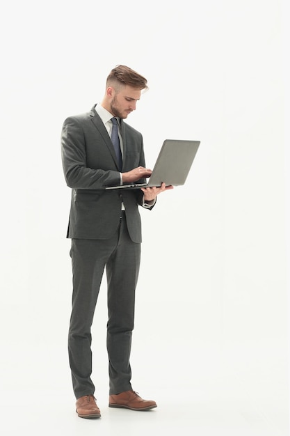 Pełnometrażowy portret biznesmena stojącego i używającego laptopa na białym tle