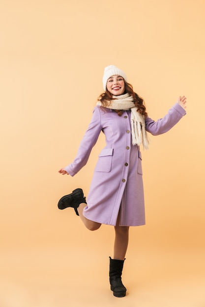 Pełnowymiarowe zdjęcie europejskiej kobiety w wieku 20 lat w zimowym ubraniu, uśmiechnięta, stojąca odizolowana