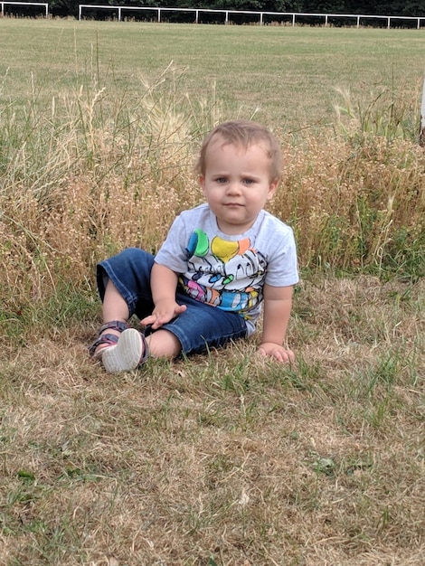 Zdjęcie pełnowymiarowy portret chłopca siedzącego na polu