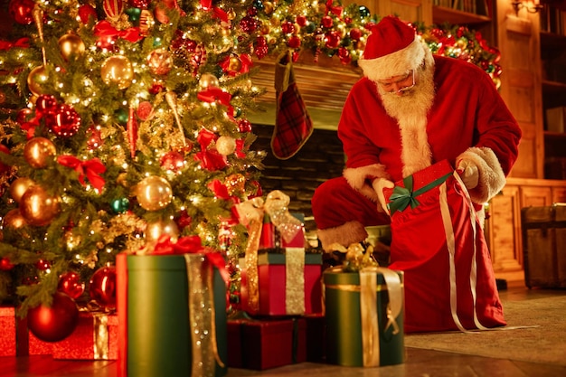 Pełnowymiarowy portret tradycyjnego Świętego Mikołaja umieszczającego prezenty pod kopią choinki