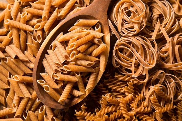 Pełnoziarniste Fusilli w łyżce. Integral Pasta na drewnianym stole