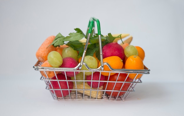 Pełny kosz na zakupy z mini owocami i warzywami