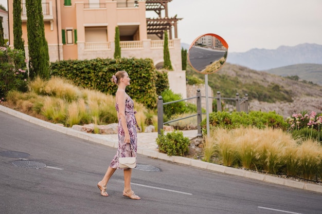 Zdjęcie pełny obraz stylowej kobiety spacerującej w czarnogórze i cieszącej się letnimi wakacjami