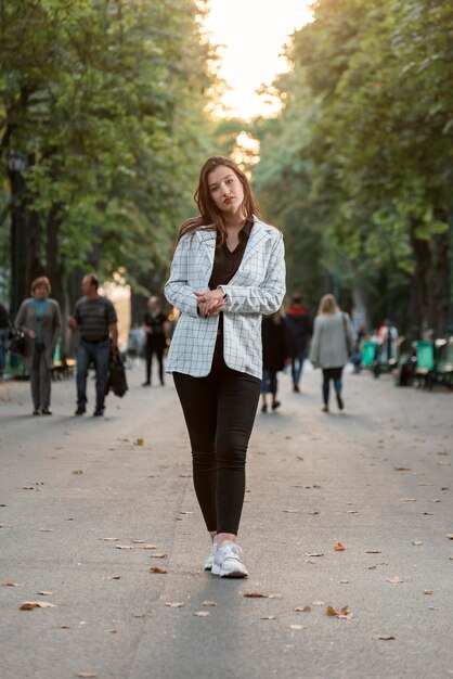Pełny portret eleganckiej młodej dziewczyny w swobodnym stylu spaceru w parku Pionowa rama