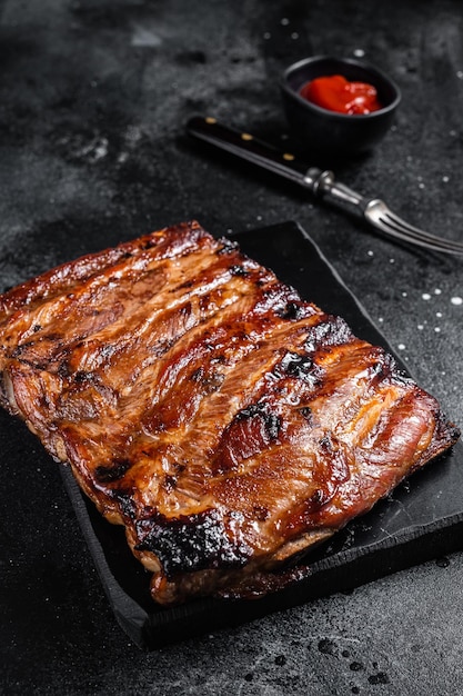 Pełny stojak BBQ grillowane żeberka wieprzowe na marmurowej desce Czarne tło Widok z góry