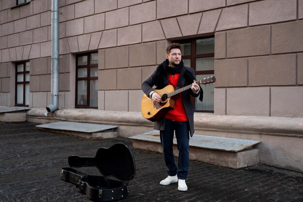 Zdjęcie pełny strzał mężczyzna grający na gitarze