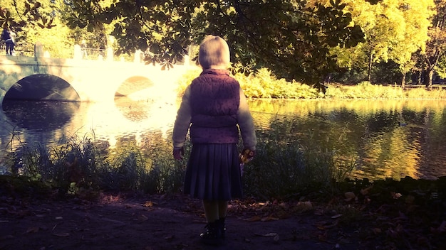 Zdjęcie pełny widok z tyłu dziewczyny idącej nad jeziorem w parku