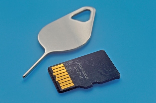 Pendrive i pin do smartfona leżą na niebieskim tle ze stykami do góry