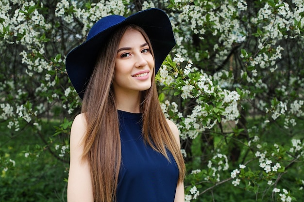 Perfect wiosna kobieta w niebieskim kapeluszu na zewn?trz U?miechni?ta dziewczyna na tle kwiatów