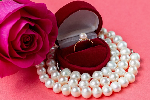 Perłowy pierścionek w pudełku w kształcie serca, naszyjnik i róża. Prezent na Walentynki