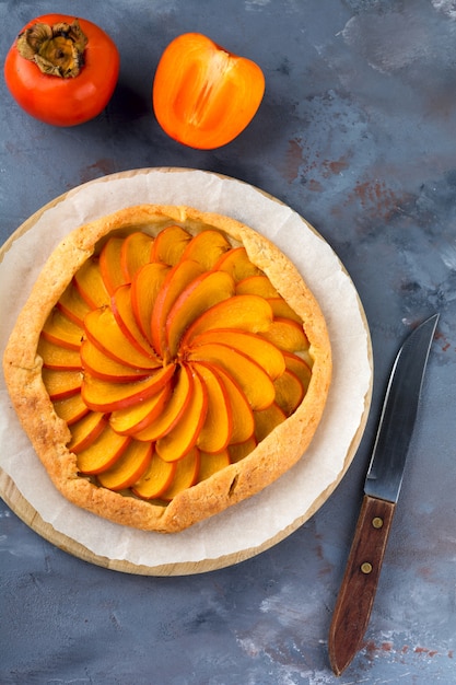 Persimmon galette, pie, tarta na szarym kamiennym tle. Widok z góry. Selektywne ustawianie ostrości.