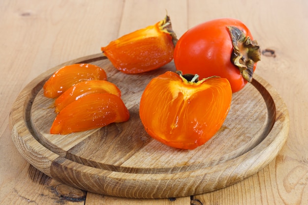 Persimmons na drewnianej desce na drewnianym tle