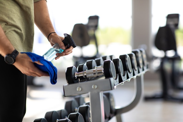 Personel fitness czyści na siłowni maszyny do ćwiczeń z alkoholowym środkiem odkażającym.