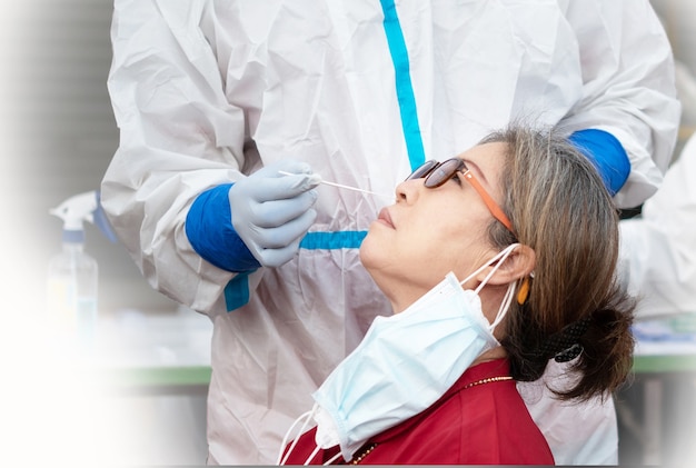 Zdjęcie personel sprawdzający starsze kobiety pod kątem koronawirusa metodą wymazu z nosa
