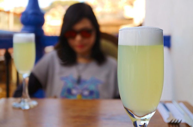 Peruwiański Pisco Sour Cocktail z rozmazaną Relaksującą młodą kobietą w Cusco Peru