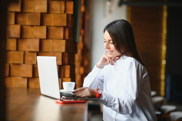 Pewna kobieta biznesu, szukając CV na stronie za pomocą laptopa, siedząc w restauracji podczas przerwy w pracy. Kobieta kierownik projektu korzystająca z aplikacji na urządzeniu przenośnym, odpoczywająca w kawiarni