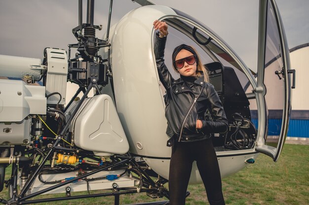 Pewna siebie animowana dziewczyna opierając się na otwartym kokpicie helikoptera