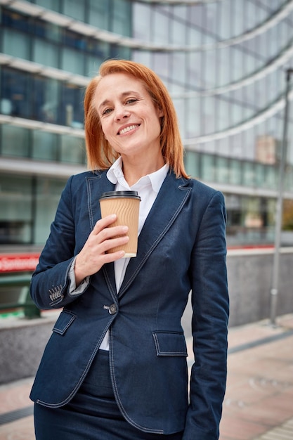Pewna siebie bizneswoman robi sobie przerwę z kawą, zyskując energię i perspektywę