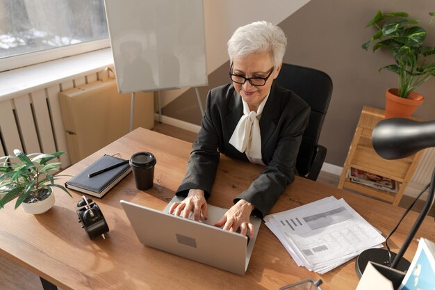 Pewna siebie stylowa europejska starsza kobieta w średnim wieku korzystająca z laptopa w miejscu pracy stylowa starsza dojrzała s