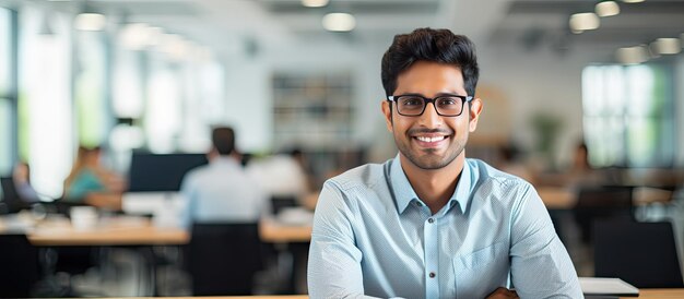 Pewny siebie indyjski biznesmen uśmiecha się do kamery w przestrzeni biurowej