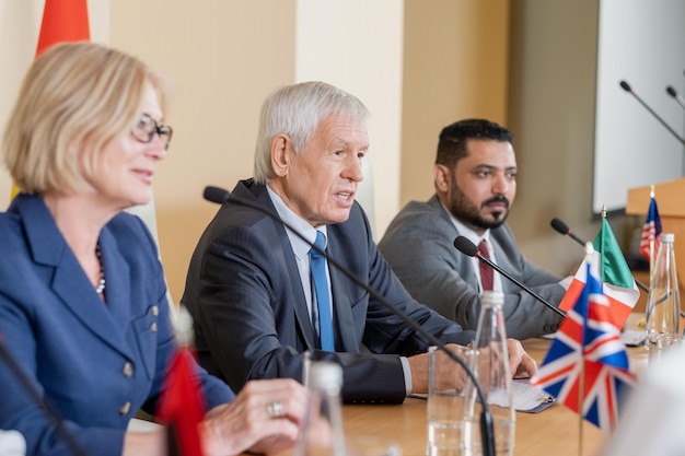 Pewny siebie starszy polityk w stroju formalnym przemawiający na konferencji