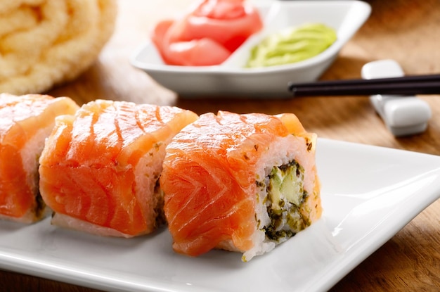 Philadelphia roll sushi na białym talerzu z wasabi i imbirem