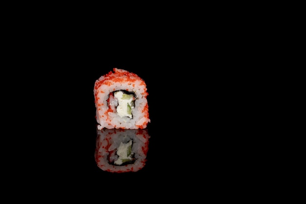 Philadelphia roll z łososiem, serem i ogórkiem na czarnym tle z odbiciem. Sushi Filadelfia