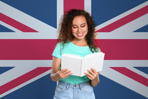 Pi?kna African American m?oda dziewczyna czyta ksi??k? i flag? Wielkiej Brytanii jako t?o Nauka angielskiego