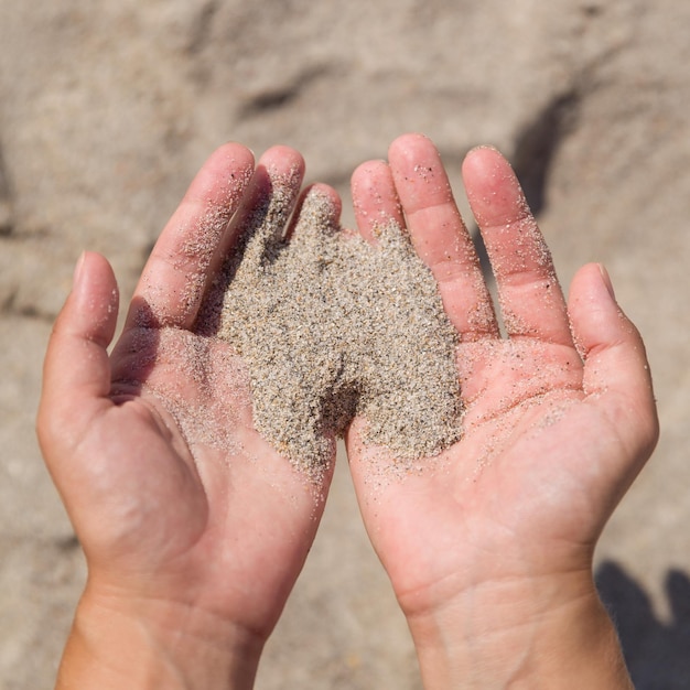 Piasek przelewa się przez ręce dziewczyny Zbliżenie Młoda kobieta z piaskiem w dłoniach