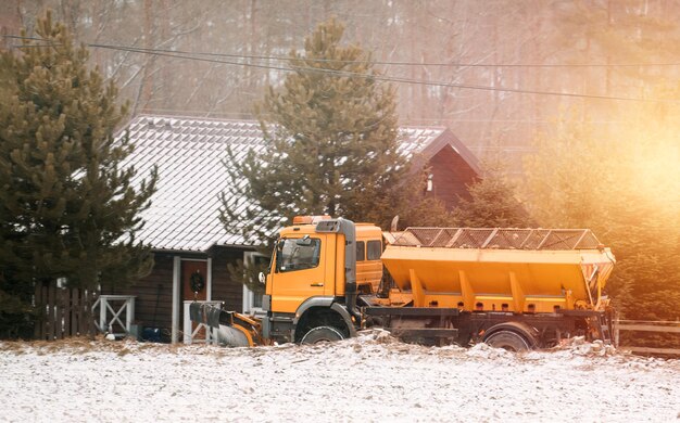 Piaskarka pracująca na podmiejskiej ulicy po obfitych opadach śniegu Odśnieżanie dróg Rozrzucanie soli