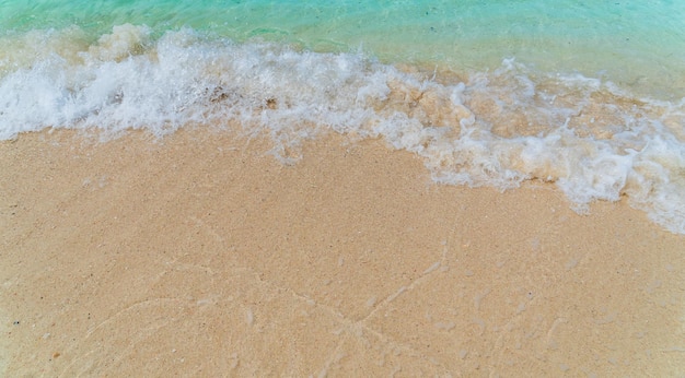 Piaszczysta plaża nadmorska z białymi spienionymi i niebieskimi falami od morza